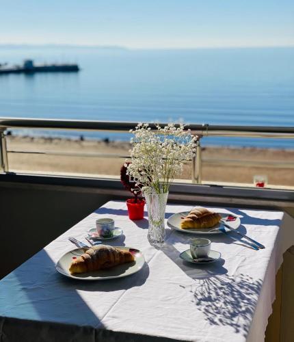 a table with two plates of croissants and a view of the ocean at Cozy Beachfront Room in Durrës