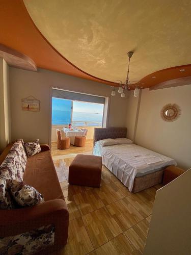 a bedroom with a bed and a couch and a window at Cozy Beachfront Room in Durrës