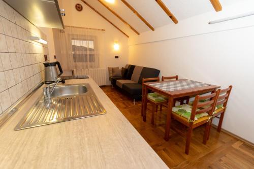eine Küche mit einem Waschbecken, einem Tisch und einem Sofa in der Unterkunft Apartman Miramare in Otočac