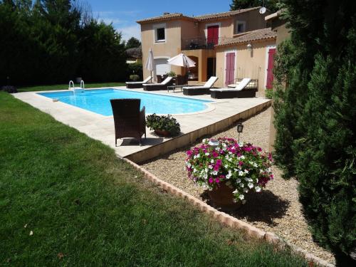 a swimming pool with chairs and flowers next to a house at Mas'Xime in Saint-Rémy-de-Provence