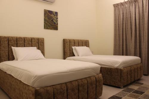 two beds sitting next to each other in a room at أمجاد للشقق الفندقية in Al Ḩuwayl