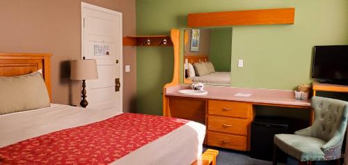 a bedroom with a bed and a sink and a mirror at James Bay Inn Hotel, Suites & Cottage in Victoria