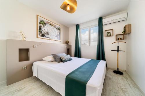 a bedroom with a white bed and a window at Les Pailles en Queue - Appartements de Charme & Standing in Sainte-Marie