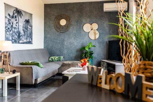 a living room with a couch and a table at Les Pailles en Queue - Vue mer - Appartements de Charme & Standing in Sainte-Marie