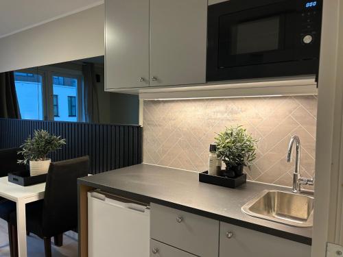 a kitchen with a sink and a microwave at Skippergata - Rooms in Kristiansand