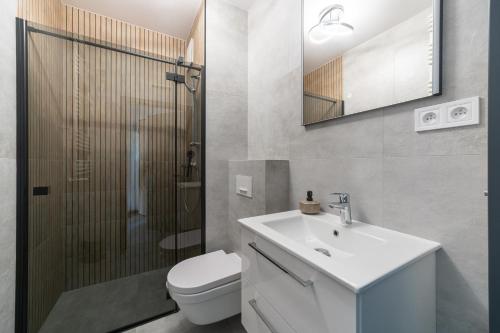 La salle de bains est pourvue de toilettes, d'un lavabo et d'une douche. dans l'établissement Nowe Apartamenty Warszawa Wiktoryn TV Smart WI-FI, à Varsovie