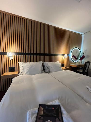 a bedroom with a large white bed and a mirror at Swiss Plus Hotel in Bihać