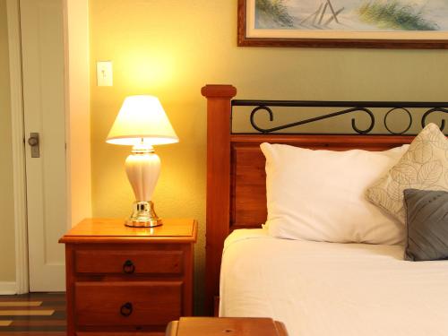 a bedroom with a bed and a lamp on a night stand at James Bay Inn Hotel, Suites & Cottage in Victoria