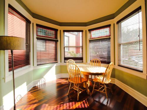 a dining room with a table and chairs and windows at James Bay Inn Hotel, Suites & Cottage in Victoria
