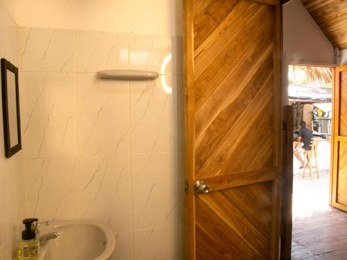a bathroom with a wooden door and a tub at Mithival Beach Rincón del Mar in Rincón
