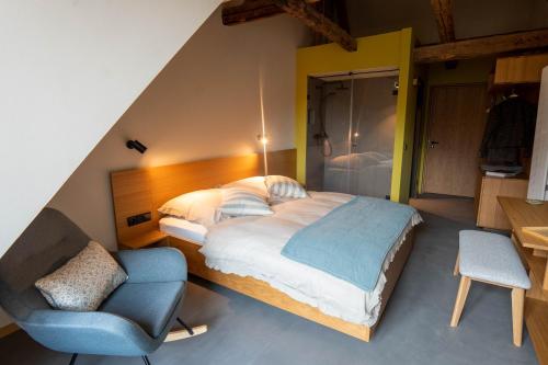 - une chambre avec un grand lit et une chaise dans l'établissement Gästehaus Liebfrauen, à Wernigerode