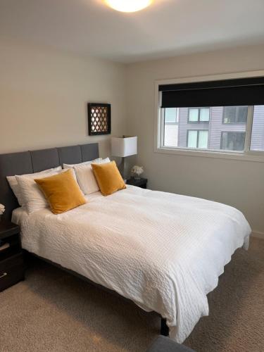 a bedroom with a large white bed with orange pillows at Cozy Haven in Winnipeg