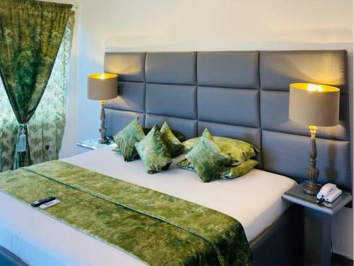 ein Schlafzimmer mit einem großen Bett mit grünen Kissen in der Unterkunft Perriman Hotel in Kokrobite