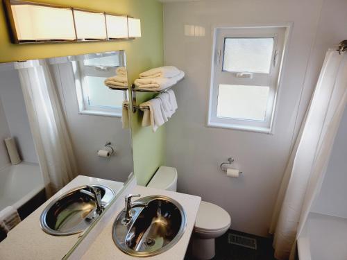 a bathroom with a sink and a toilet and a mirror at James Bay Inn Hotel, Suites & Cottage in Victoria