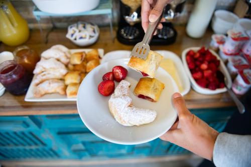 a person holding a plate of food with strawberries and bread at Viento Bravo Hotel Boutique & Spa in Pichilemu