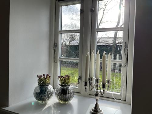 a window with two vases and a candle on a counter at Lindegaardens Bed and Breakfast in Viby