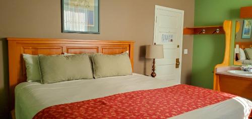 a bedroom with a large bed with a red blanket at James Bay Inn Hotel, Suites & Cottage in Victoria