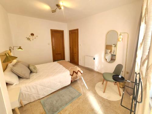 een slaapkamer met een bed, een stoel en een spiegel bij Acogedor apartamento para dos en el centro in Huesca
