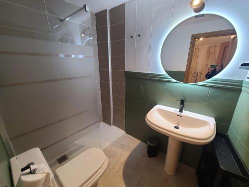 een badkamer met een wastafel, een toilet en een spiegel bij Acogedor apartamento para dos en el centro in Huesca