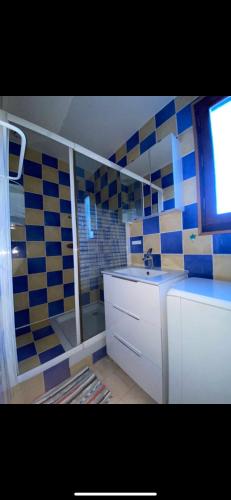 La salle de bains est pourvue d'un lavabo et d'un mur en carrelage bleu et blanc. dans l'établissement Maison avec jardin Résidence Horizon Bleu Vendres, à Vendres