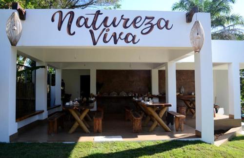 a sign for a restaurant with wooden tables and chairs at Pousada Natureza Viva in Itacaré