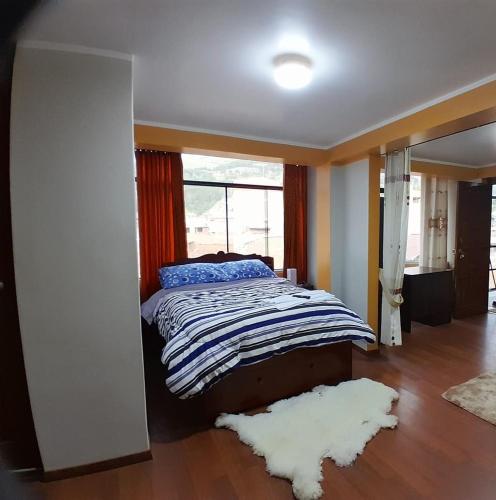 a bedroom with a bed and a window and a rug at MINIDEPARTAMENTO SICUANI in Sicuani
