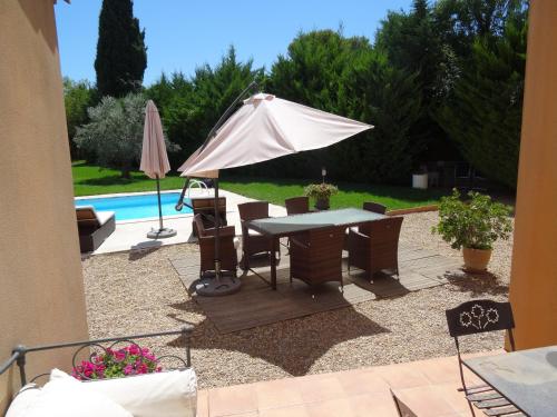 a patio with a table and an umbrella next to a pool at Mas'Xime in Saint-Rémy-de-Provence