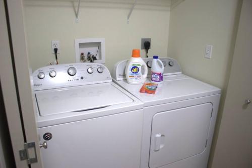 eine weiße Waschmaschine und ein Trockner mit Reinigungsmitteln darauf in der Unterkunft Athens city townhouse, 2 King masters, 2.5 baths in Athens