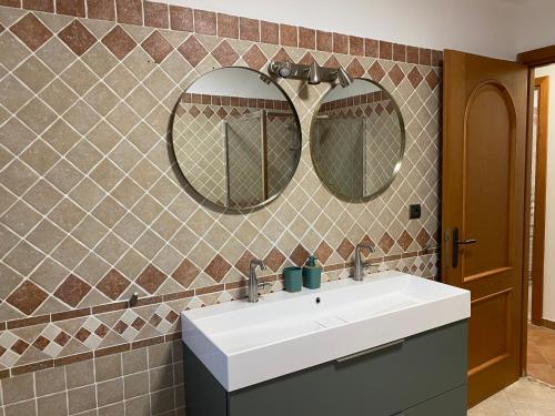 une salle de bain avec un lavabo blanc et deux miroirs dans l'établissement Appartements 300 mètres de la mer et villa, à Saint-Florent