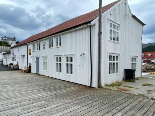 a large white building with a wooden deck at 1. etg i Dampskipsbrygga, Lødingen havn in Lødingen