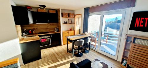 una cucina con tavolo e vista su un balcone di Cozy Studio Retreat - completely renovated in a perfect location a Crans-Montana