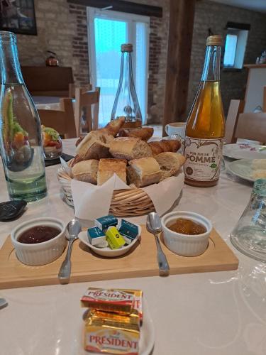Una mesa con una bandeja de pan y botellas de refresco. en Chambres d'hôtes Le Clos Poli, en Montigny-les-Monts
