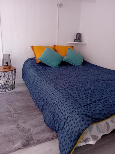 - un lit avec des oreillers bleus et oranges dans l'établissement maison de vacances tout confort, au Cap d'Agde