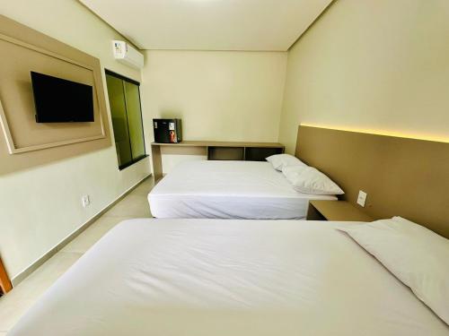 um quarto de hotel com duas camas e uma televisão de ecrã plano em POUSADA ALTER PARA TODOS em Alter do Chão