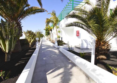 a sidewalk with palm trees next to a white building at Apartamentos Aloe in Puerto del Carmen