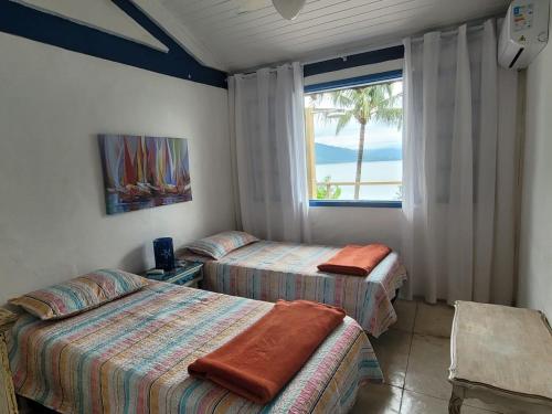 um quarto com 2 camas e uma janela com uma palmeira em ILHABELA Vista Panorâmica em Ilhabela