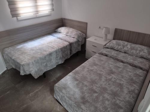 a bedroom with two beds and a nightstand and a bed sidx sidx sidx sidx at Casa Elai in Sant Carles de la Ràpita