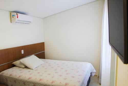 a small bedroom with a bed and a television at Suite na Morada do Sol in Piratuba