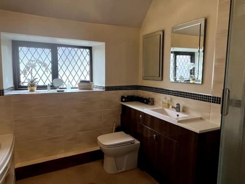 a bathroom with a toilet and a sink and a window at Grace Dieu Cottage - Sleeps 7 in Whitwick