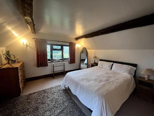 een slaapkamer met een groot wit bed en een raam bij Grace Dieu Cottage - Sleeps 7 in Whitwick
