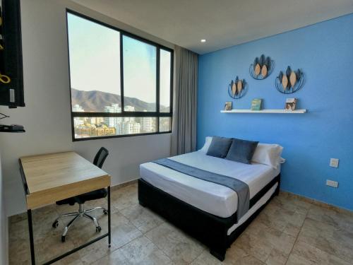 a bedroom with a bed and a desk and a window at Puro Confort en el Rodadero Santa Marta in Rodadero