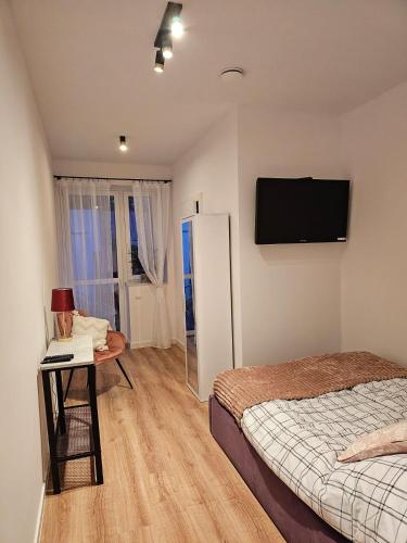 a bedroom with a bed and a television on the wall at Pokoje przy Parkowej in Zwierzyniec