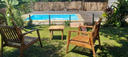2 Stühle und ein Tisch im Garten mit Pool in der Unterkunft Cabaña Don floricel in Santa Ana