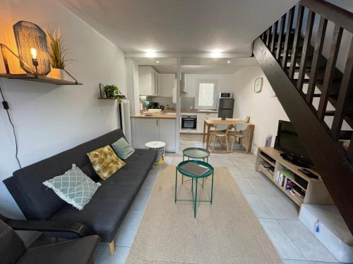 - un salon avec un canapé noir et un escalier dans l'établissement Agréable maison entre lac et océan à Lacanau, à Lacanau