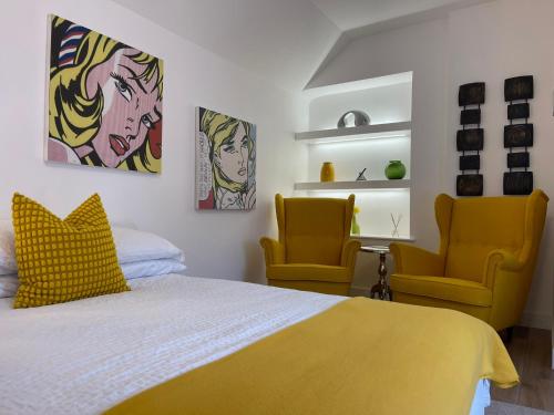 a bedroom with a bed and two yellow chairs at Vibrant Apartments Close to City Centre in Cardiff