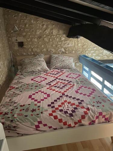 une chambre avec un lit avec une couette dessus dans l'établissement Location Mortagne -Sur Gironde, à Mortagne-sur-Gironde