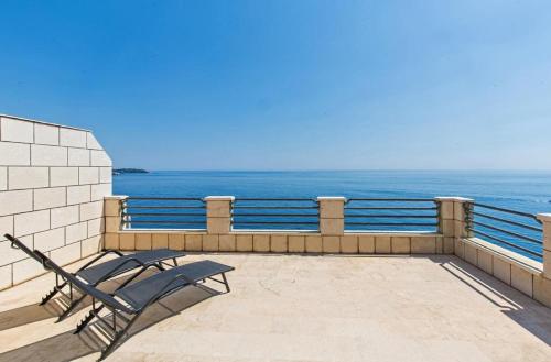 a chair sitting on a balcony overlooking the ocean at Big Blue Apartments in Dubrovnik