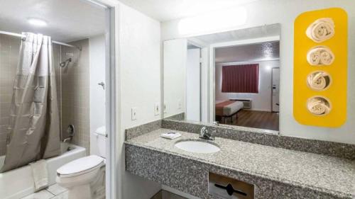 een badkamer met een wastafel, een toilet en een spiegel bij Whitten Inn in Clinton