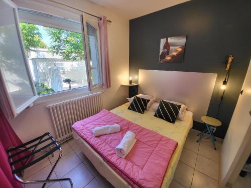 Un pequeño dormitorio con una cama rosa y una ventana en Gîte VENITIA, en Aussonne
