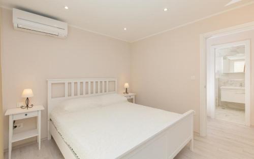 a white bedroom with a white bed and a window at Big Blue Apartments in Dubrovnik